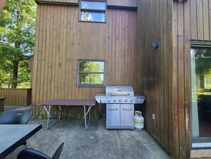 An outdoor patio with a grill, a table, and chairs. - Lakefront Chalet in Montreal (Montréal)