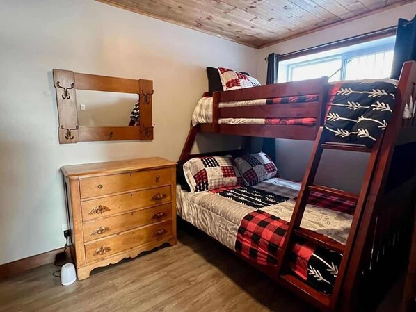 A bunk bed with a checkered blanket, a wooden dresser with drawers, and a mirror on the wall. - Lakeside Drolet - Spa - Par Grand Vents (Lac-Drolet)