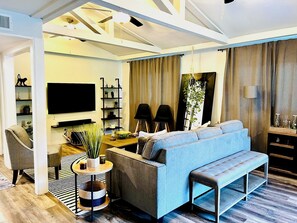 A modern living room with a blue sofa, a wooden coffee table, a TV, and a bookshelf. - Family home in Dallas’s most prestigious neighborhood - Preston Hollow! 3 BR/2BA (Dallas)