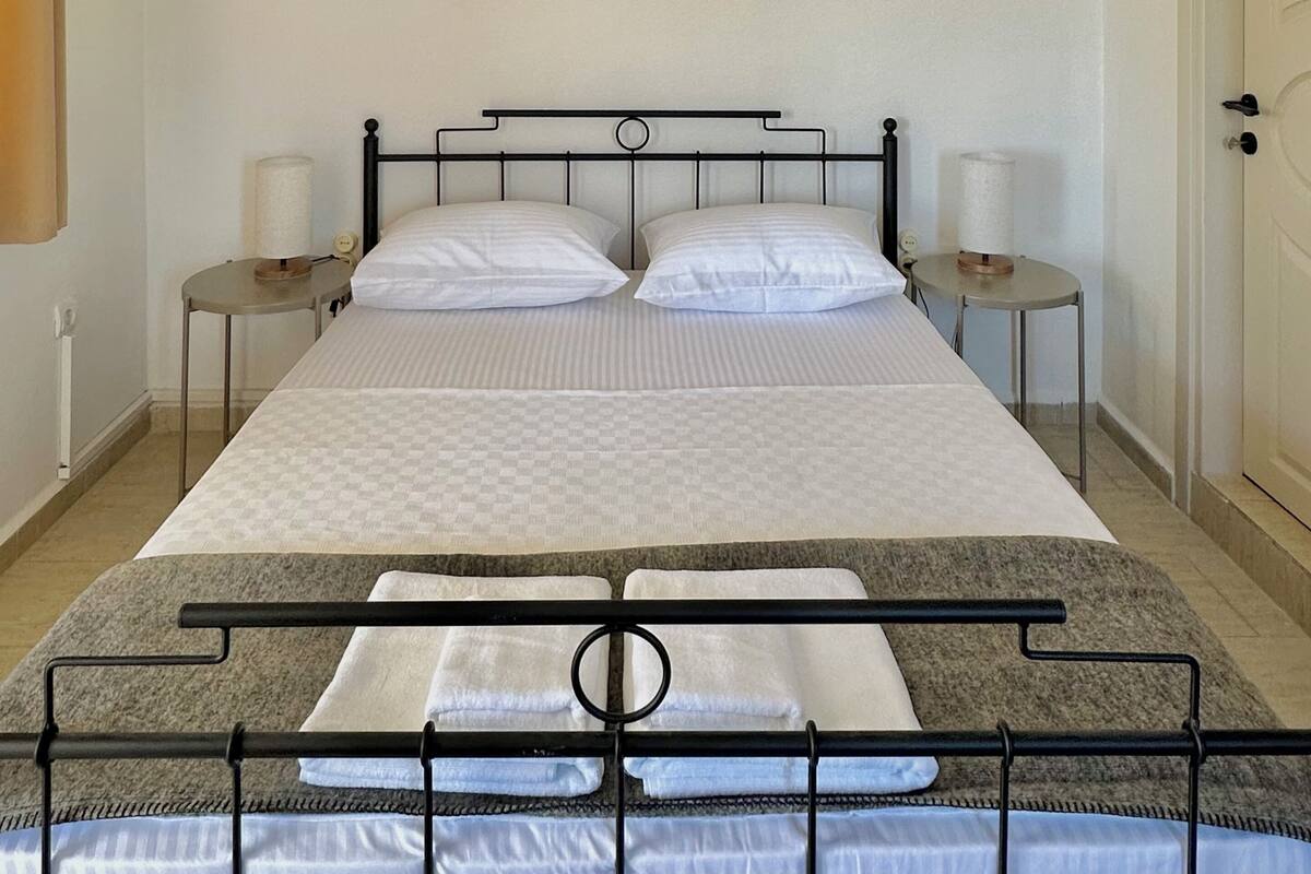 A bed with a metal frame, two bedside tables, and three framed artworks on the wall.