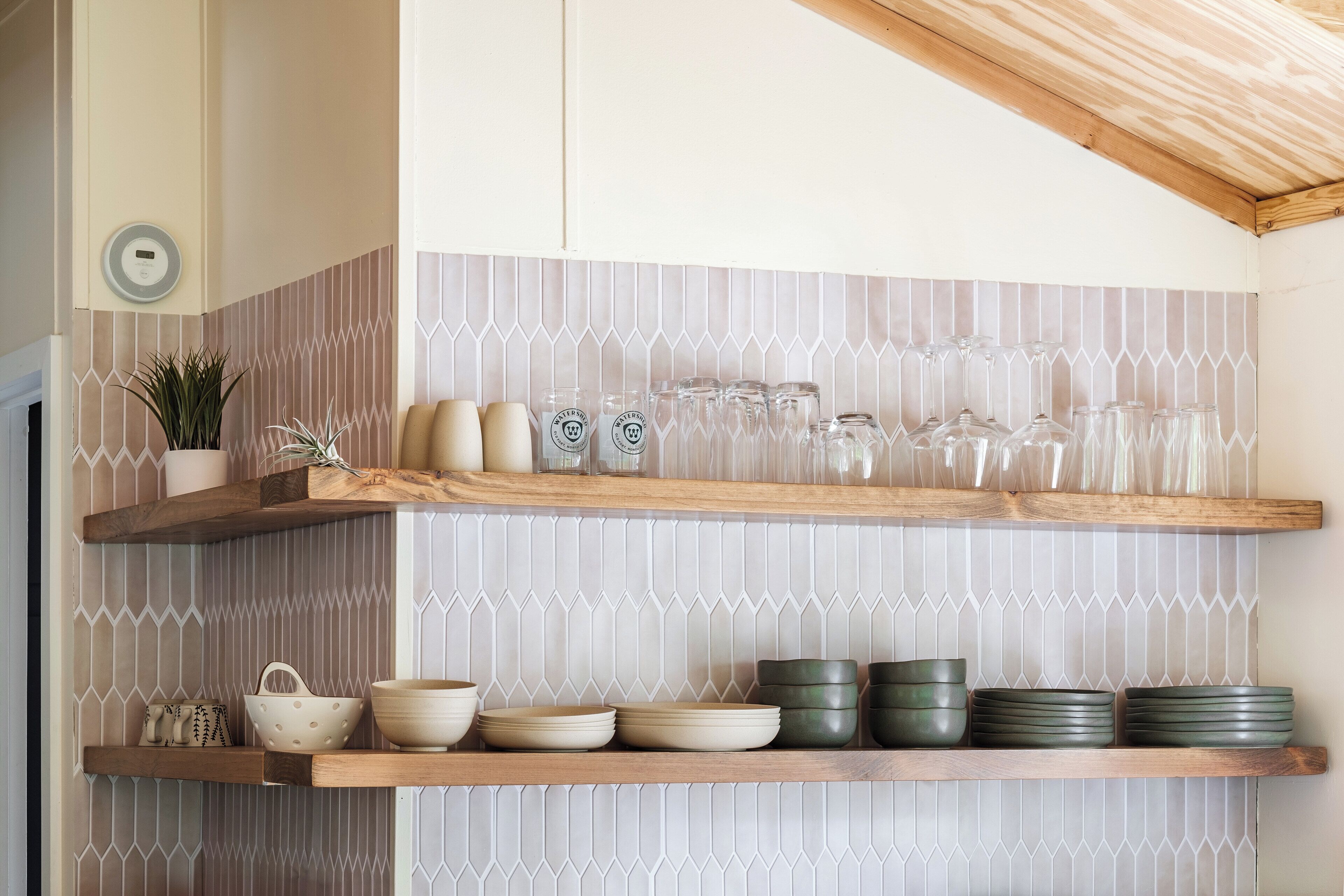 Una cocina con repisas de madera que contienen cristalería y platos.