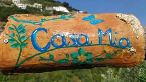 Ein hölzernes Schild mit dem Schriftzug 'Casa Mia' und dekorativen floralen Mustern.