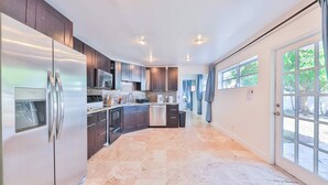 A modern kitchen with dark cabinets, stainless steel appliances, and a large island.