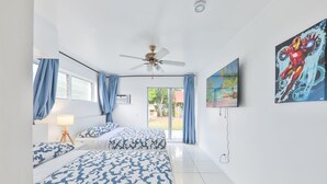 A hotel room with two beds, a ceiling fan, a TV, and a large window with curtains.