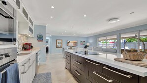 A modern kitchen with a large island, built-in appliances, and a view to the outside.