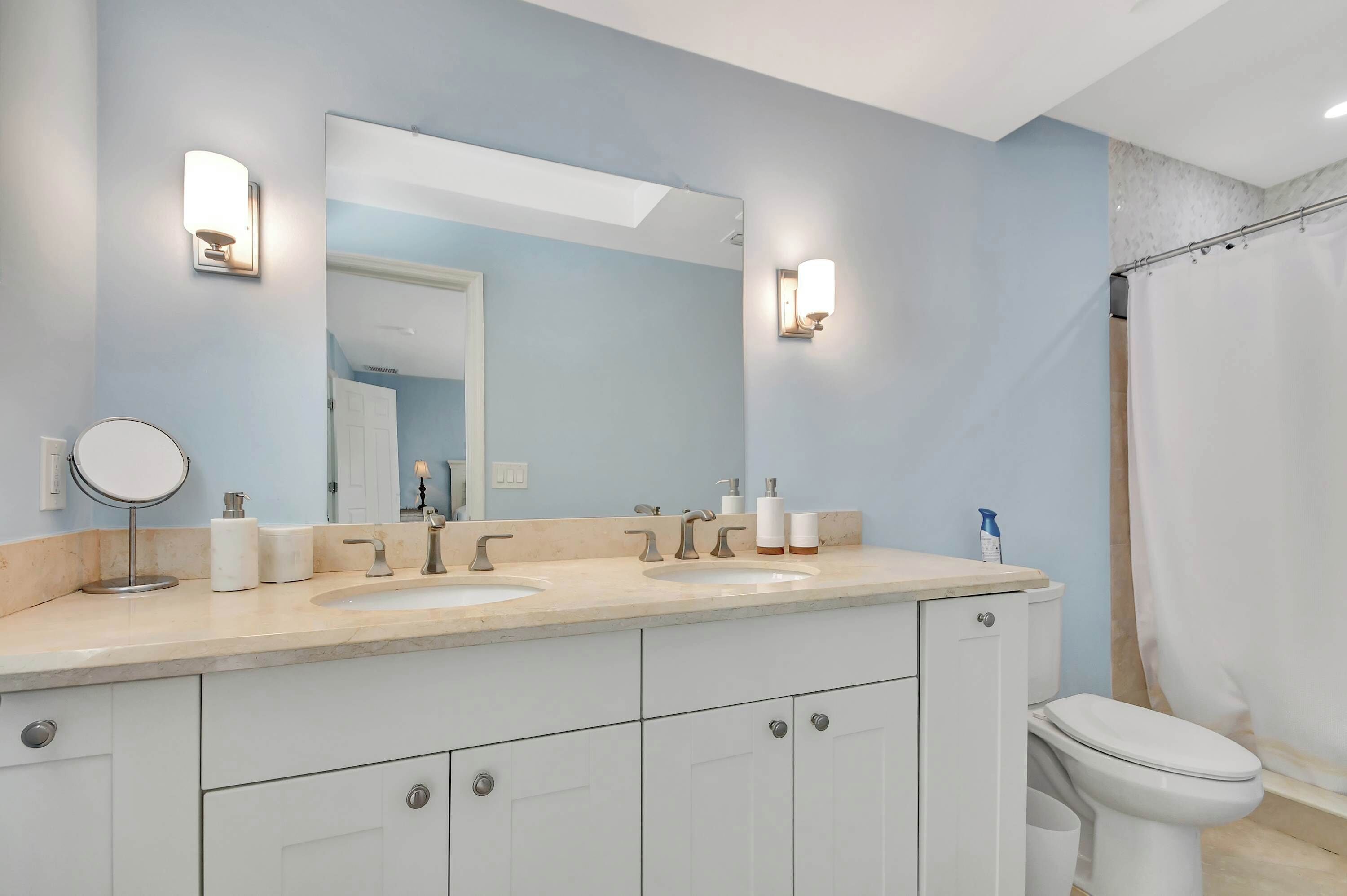 A bathroom with two sinks, a large mirror, and a toilet.