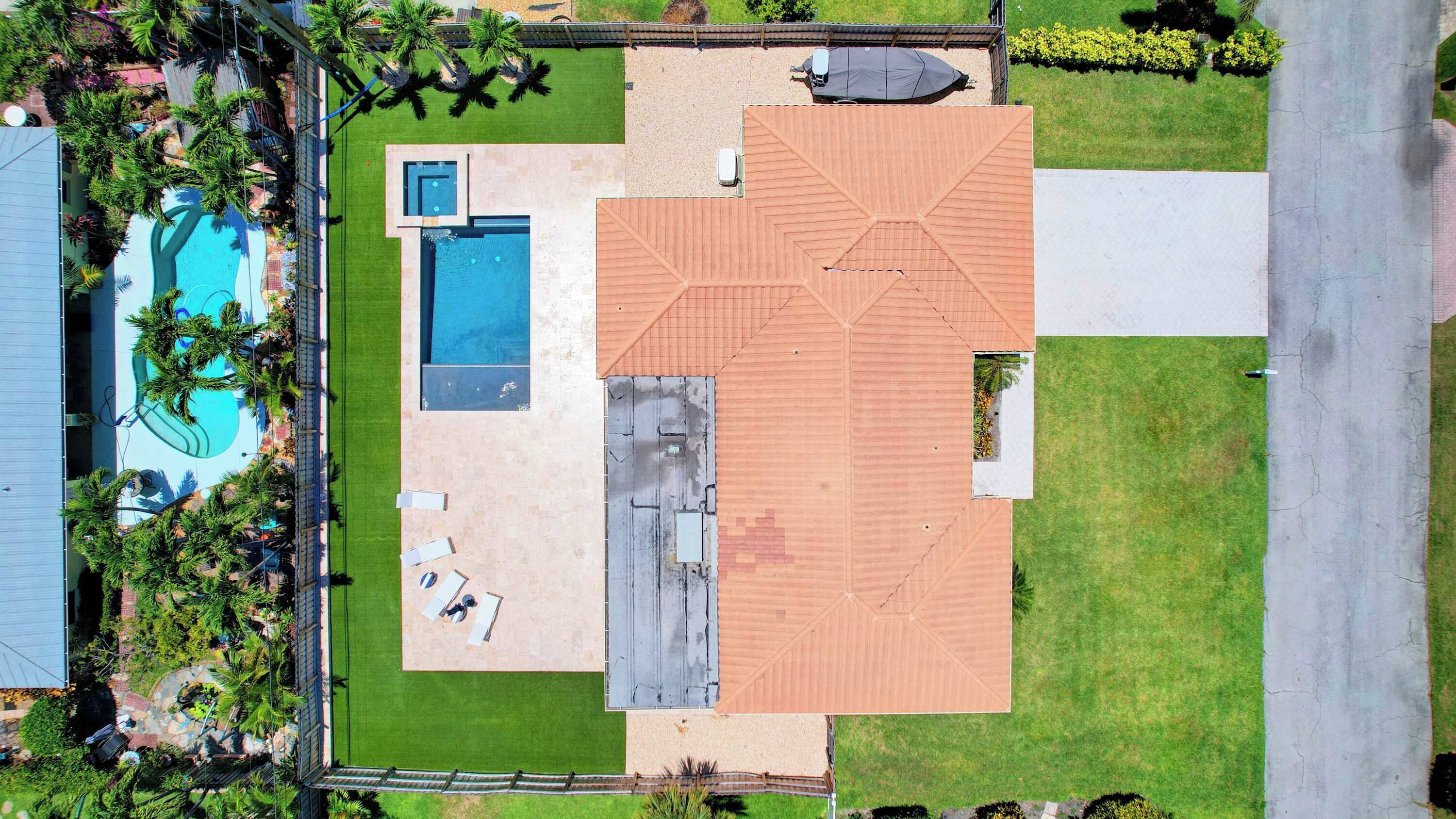 Vista aérea de una propiedad con piscina, terraza cubierta y amplio césped.