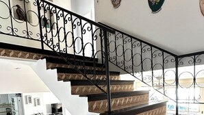 Interior com vários níveis e escadaria com grades ornamentadas em preto.