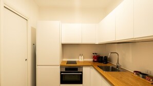 A compact kitchen with white cabinets, a wooden countertop, a stainless steel sink, a toaster, and an oven.