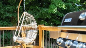A wooden deck with a hanging chair and a barbecue grill. - Family Cottage with 4 King Beds and Fire Pit, Norwalk/Westport Border (Norwalk)