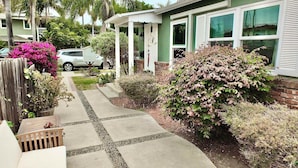 A residential house with a paved driveway, a wooden fence, and various plants. - Greenbelt Guesthouse (Long Beach)