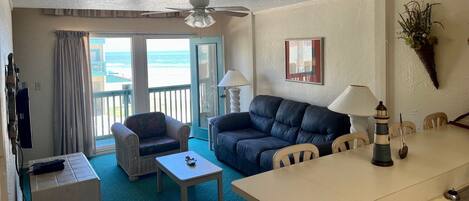 A room with a balcony, a sofa, a table, and a lamp.