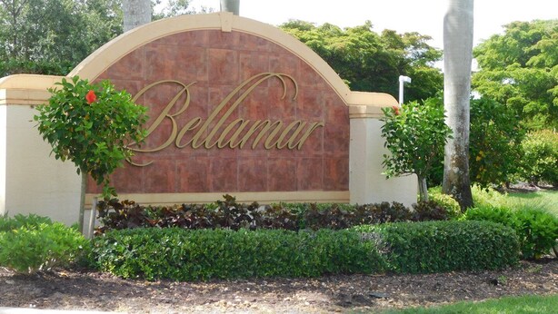 Une enseigne portant le nom « Bellamar », écrit dans une police décorative, et entourée de verdure et de palmiers.