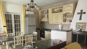 A kitchen with a dining area, featuring a marble countertop, white chairs, and a yellow sofa. - Hssoverato - Camera Matrimoniale (Soverato)