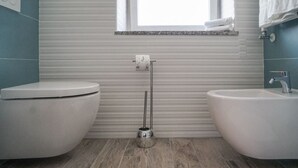 Une salle de bain équipée de toilettes, d’un bidet et d’un lavabo.