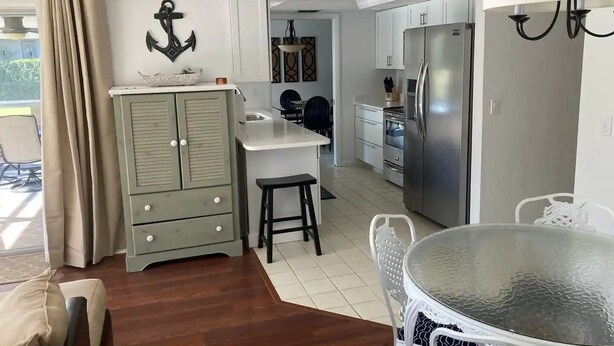 A compact kitchen with a dining area, a refrigerator, and a small island. - Beautiful Naples home, walk to private beach! (Naples)