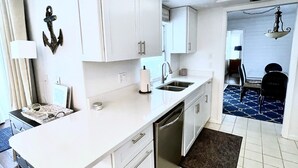 A modern kitchen with white cabinetry, a central island, and a ceiling fan. - Beautiful Naples home, walk to private beach! (Naples)