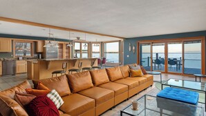 Ein großzügiger Wohnbereich mit einer großen Couch, einem Couchtisch und Meerblick durch große Schiebetüren.