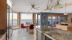 Eine Küche mit einer großen Kochinsel, ein Essbereich mit Meerblick und einem Deckenventilator.