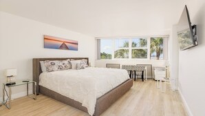 A bedroom with a large bed, a desk, and a TV mounted on the wall. - Escape to paradise at our beachfront condo at the Gulfview. (Marco Island)