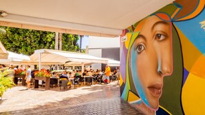 An outdoor café with tables and chairs under umbrellas, surrounded by greenery. - Cubo's Estudio Malaga Center / city center / air conditioning / free wifi (Málaga)