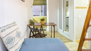 A narrow room with a bed, a small table with a plant, two chairs, and a wooden ladder. - Cubo's Estudio Malaga Center / city center / air conditioning / free wifi (Málaga)