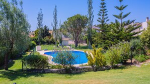A landscaped garden with a swimming pool, surrounded by various trees and shrubs. - Cubo's Townhouse Sierrezuela / communal pool / BBQ / terrace / parking (Mijas Costa)