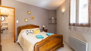 Een slaapkamer met een houten bed, nachtkastjes, een wandplank en een radiator.