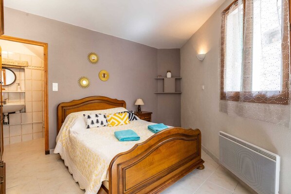 Un dormitorio con cama de madera, mesitas de noche, estante en la pared y radiador.