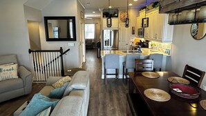 Un salón amplio con sofá, mesa de comedor y cocina al fondo.