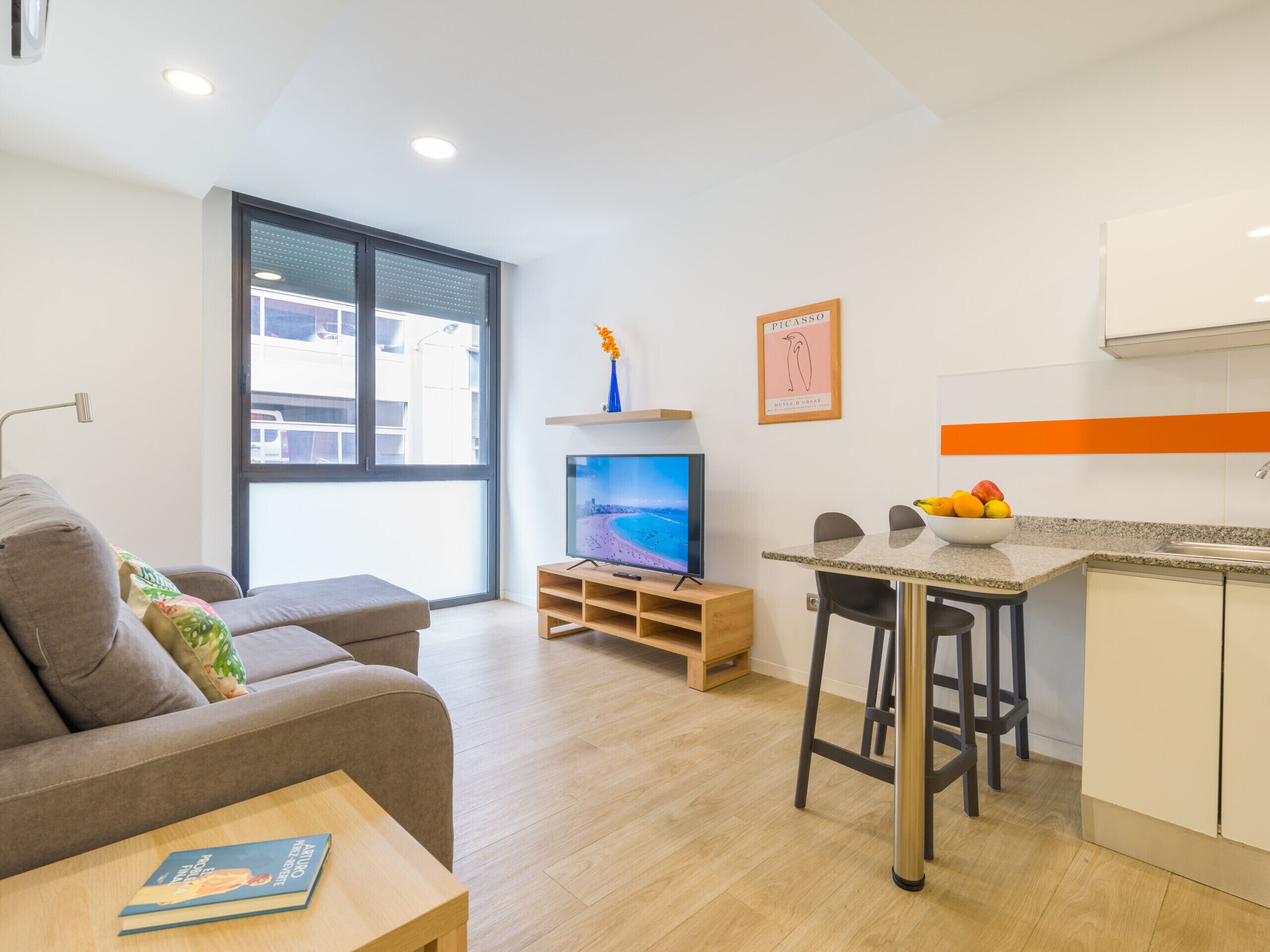 A modern living room with a sofa, a TV, and a dining area with a table and chairs.