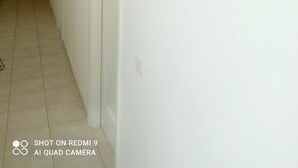 Ein Flur mit drei gerahmten Kunstwerken an der Wand, einer Tür am Ende und einem gefliesten Boden.