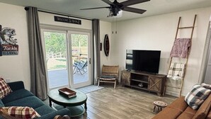 A cozy living room with a blue sofa, a brown sofa, a wooden coffee table, a wicker chair, and a television. - Waterfront Multi-family Retreat (Crystal River)