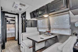 Un intérieur de camping-car compact comprenant un coin cuisine, un espace repas et un coin nuit.
