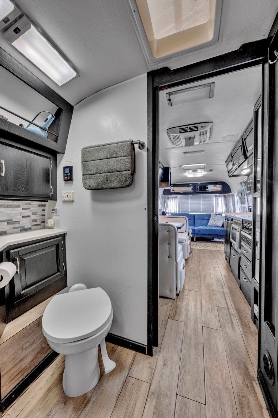 A compact kitchen with a white toilet, a small sink, and a microwave.
