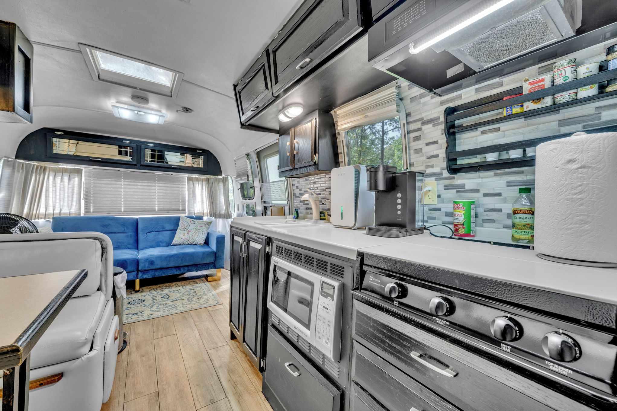 Une cuisine compacte pour camping-car, équipée d’un four à micro-ondes, d’une machine à café et d’une cuisinière.