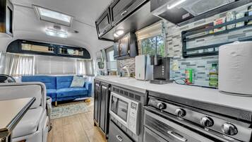 Une cuisine compacte pour camping-car, équipée d’un four à micro-ondes, d’une machine à café et d’une cuisinière.