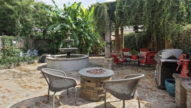 An outdoor patio with stone flooring, a circular fire pit, wicker chairs, and a grill area. - Charming 2-bedroom apartment with AC, WiFi in wonderful New Orleans (New Orleans)