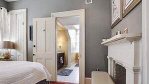 A bedroom with a bed, a bench, a fireplace, and a hallway leading to another room. - Charming 2-bedroom apartment with AC, WiFi in wonderful New Orleans (New Orleans)