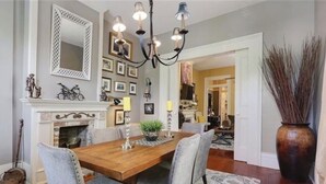 A dining room with a wooden table, grey upholstered chairs, a chandelier, and a fireplace. - Charming 2-bedroom apartment with AC, WiFi in wonderful New Orleans (New Orleans)