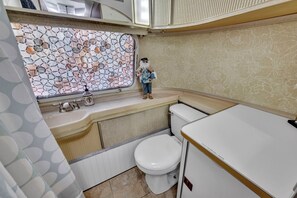 Casa de banho compacta com sanita, lavatório e parede decorativa em mosaico.