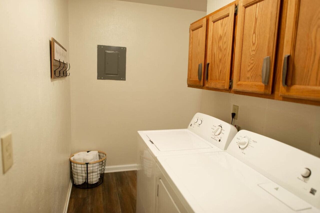 A laundry room with wooden cabinets, a white washing machine, and a metal utility panel.
