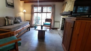A cozy living room with a sofa, wooden chairs, a table, and a fireplace. - El Viejo Cipres (San Carlos de Bariloche)
