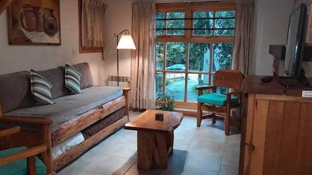 A cozy living room with a wooden sofa, a wooden coffee table, a chair, and a lamp. - El Viejo Cipres (San Carlos de Bariloche)