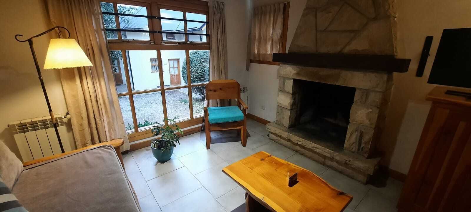 Una sala de estar acogedora con chimenea de piedra, una mesa de madera, un sofá y una silla.