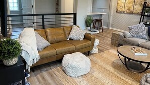 A living room with a brown sofa, a round coffee table, and a beige rug. - Lake Life! (Wautoma)