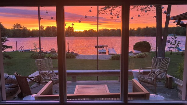 A view from a room with large windows overlooking a lake at sunset. - Lake Life! (Wautoma)