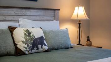 A bed with a wooden headboard, two pillows, a lamp, and a small table with a vase.