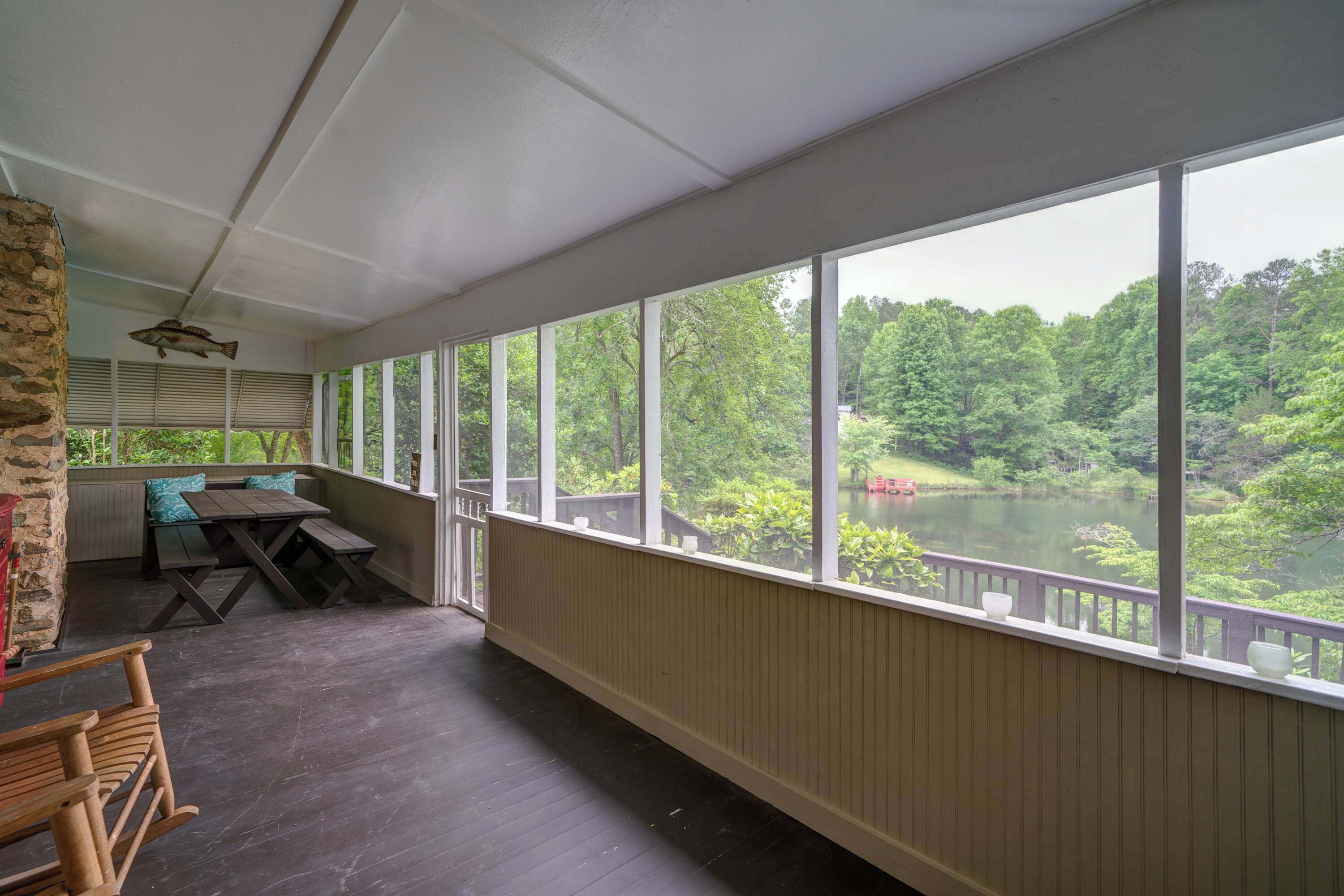 Een overdekt terras met uitzicht op een meer en bos.