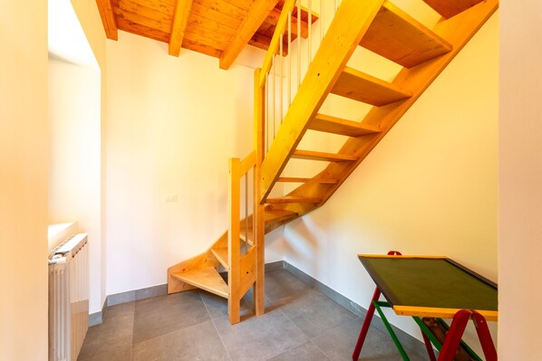 A wooden staircase in a room with a radiator and a green table.